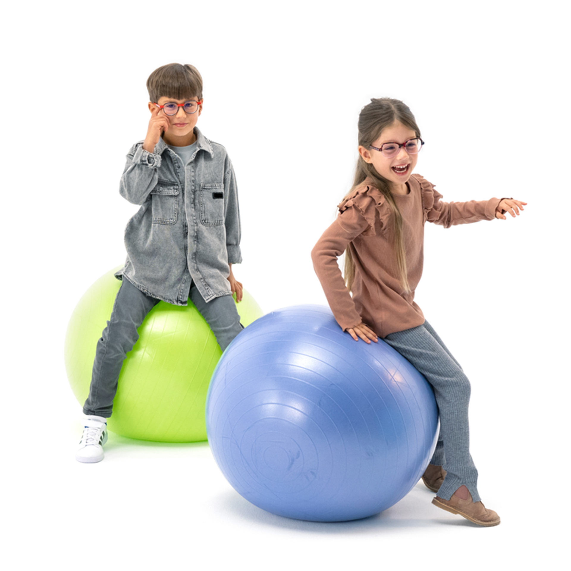 Un băiat și o fată, ambii purtând ochelari, se joacă cu mingi de gimnastică.